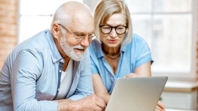A senior man and woman wearing blue shirts looking at a computer as they research COAs for their CBD products.