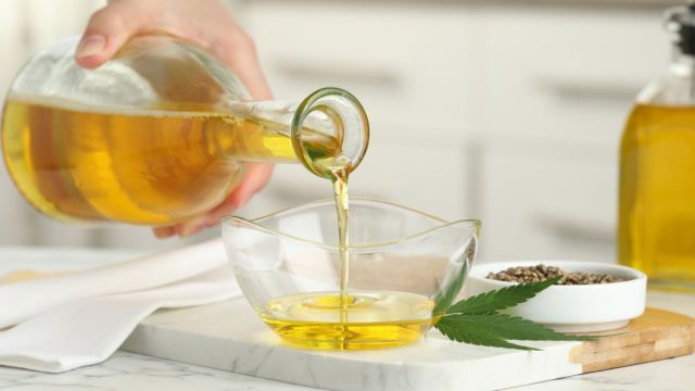 Woman pouring cannabis oil into a glass bowl for cooking