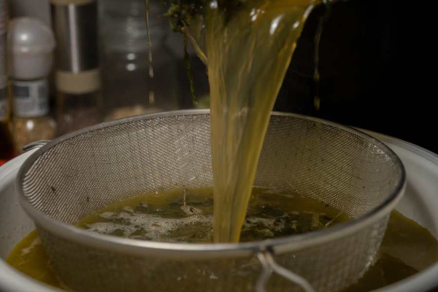 Straining cannabis oil with a fine mesh sieve. 