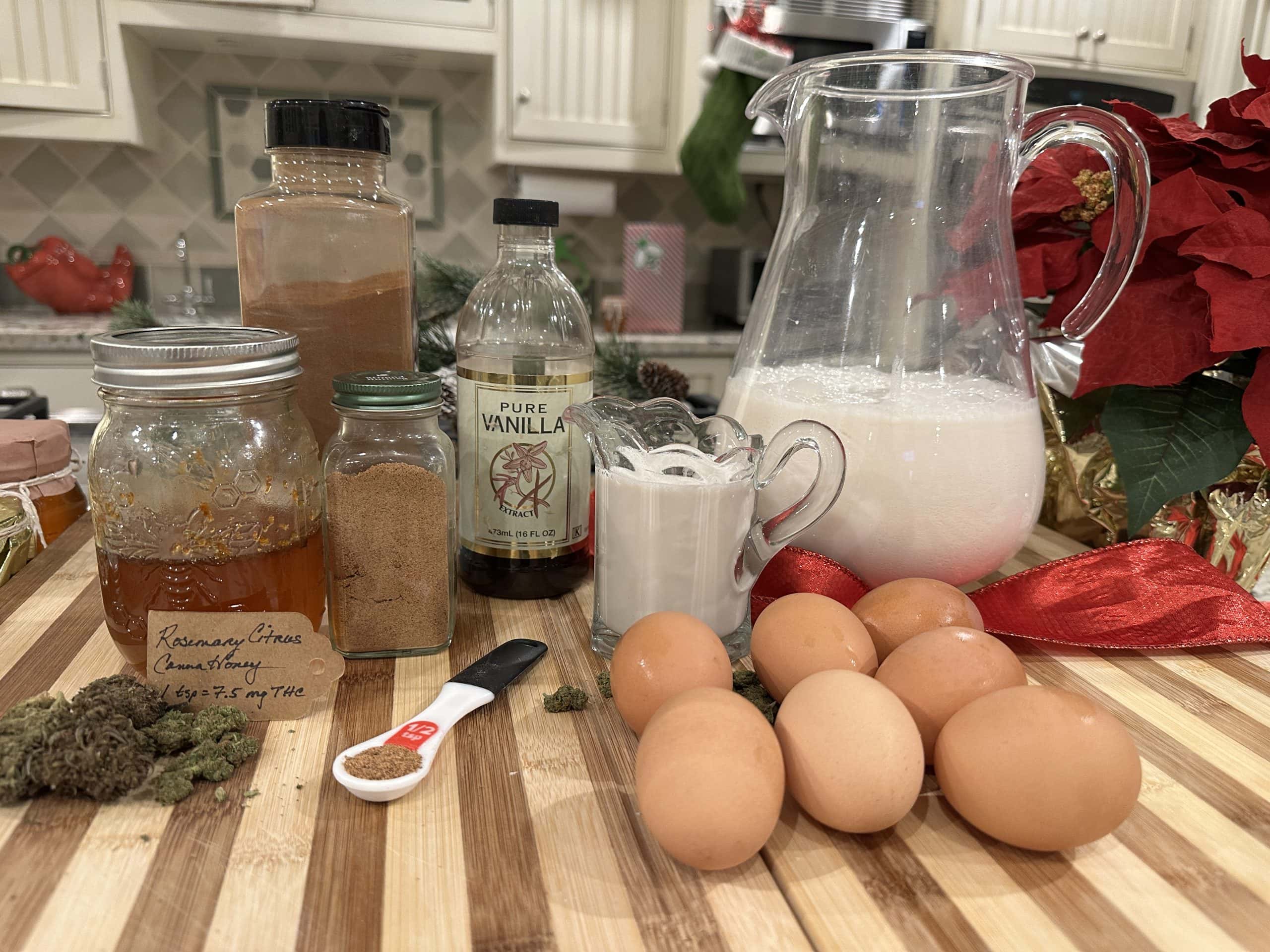 Ingredients for cannabis-infused eggnog arranged on a wooden board, including eggs, milk, cream, infused honey, vanilla extract, nutmeg, and cinnamon.