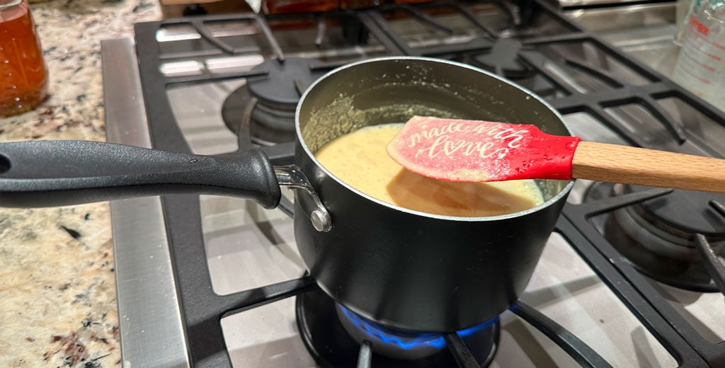 Gently thickening eggnog custard in a saucepan over low heat while stirring to prevent boiling.