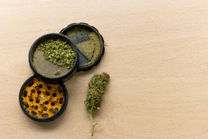 a grinder full of kief with a bud next to it