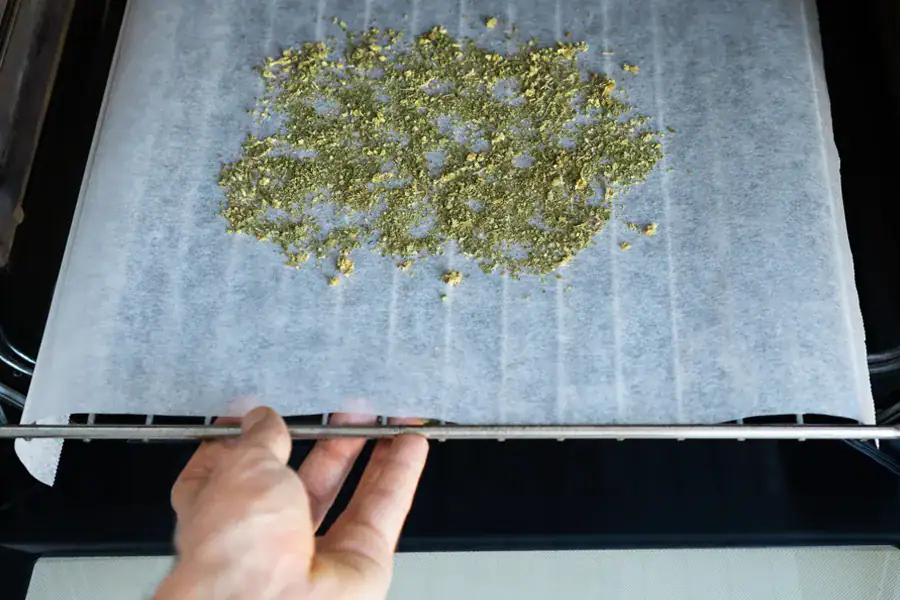 Ground cannabis spread evenly on parchment paper on a baking tray inside an oven for decarboxylation