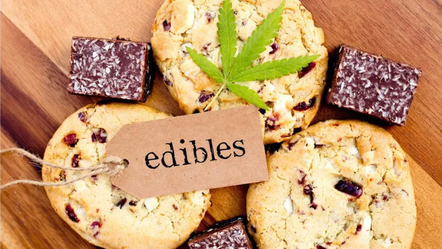 Cannabis-infused cookies and chocolate edibles displayed on a wooden surface.