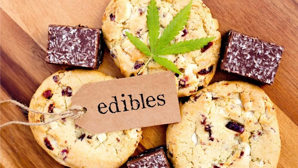 Cannabis-infused cookies and chocolate edibles displayed on a wooden surface.