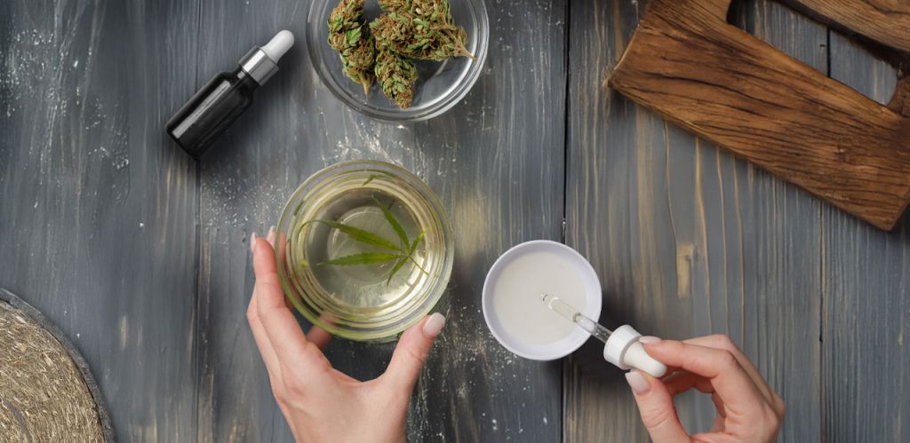 overview of a woman hands making CBD oil on a wooden table top