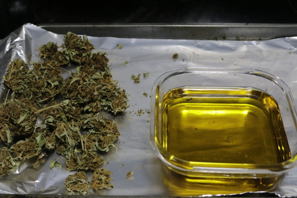 Cannabis flower spread on foil-lined baking sheet for decarboxylation in the oven
