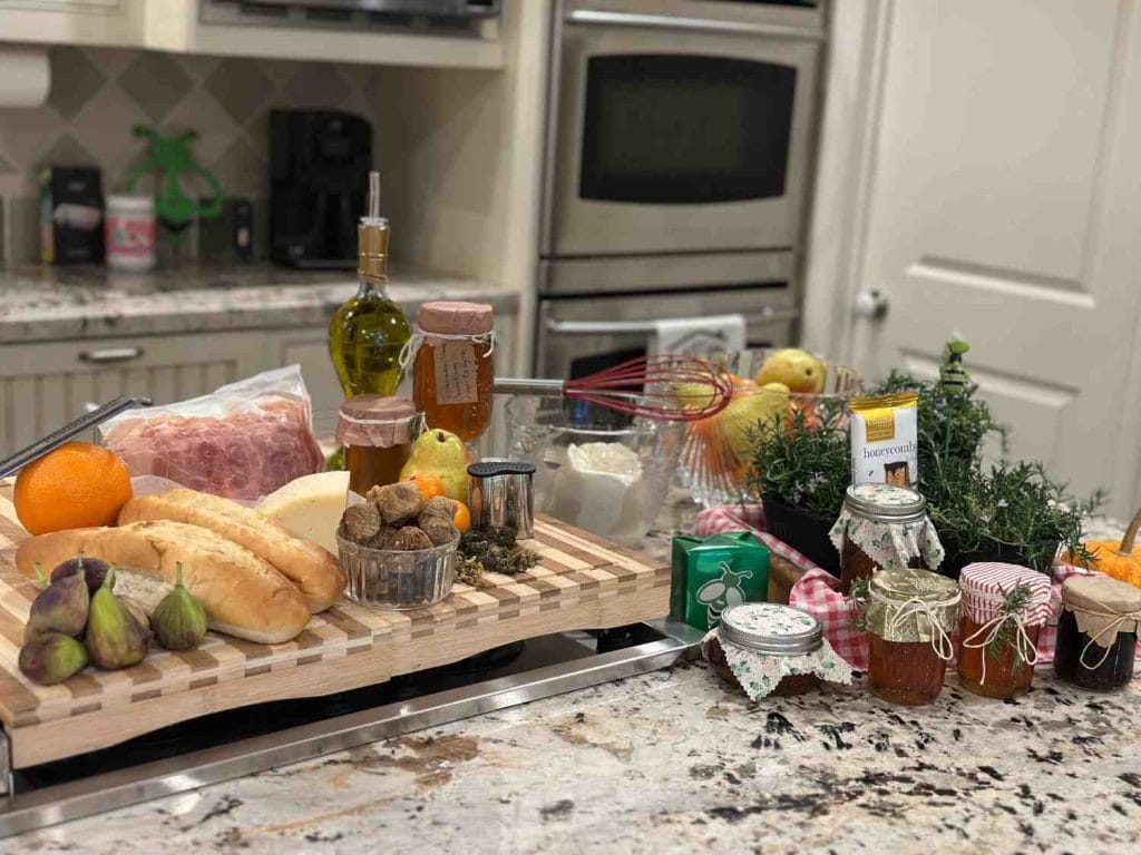 Fresh ingredients for homemade cannabis oil, butter, and honey infusions displayed on a kitchen counter — including olive oil, herbs, honey jars, figs, and citrus.