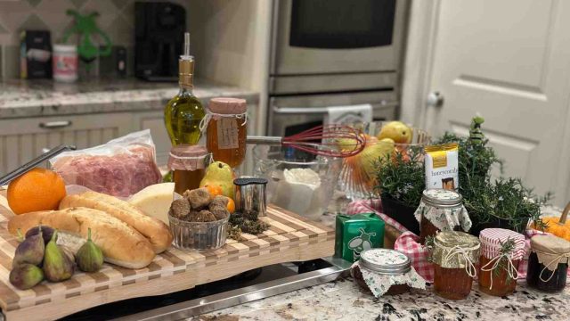Fresh ingredients for homemade cannabis oil, butter, and honey infusions displayed on a kitchen counter — including olive oil, herbs, honey jars, figs, and citrus.