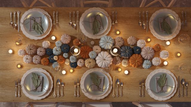 Top-down view of an elegant Thanksgiving table setting decorated with neutral and colorful mini pumpkins, candles, and neatly arranged dinner plates for a festive holiday meal.