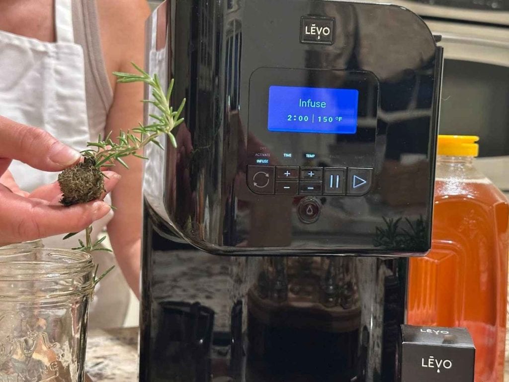 LĒVO oil infuser during the infusion process with herb pod and oil reservoir, demonstrating precise temperature control for cannabis infusions.